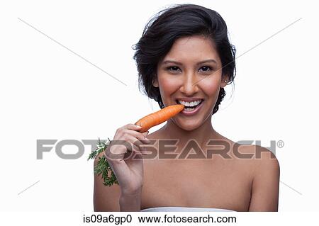 Stock Image - Young woman biting carrot. Fotosearch