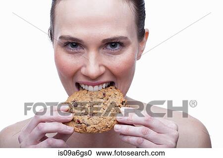 Stock Image - Young woman biting cookie. Fotosearch