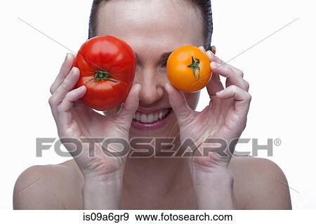 Young woman covering eyes with red and yellow tomato View Large Photo Image Stock Photo - Young woman covering eyes with red and yellow tomato. Fotosearch