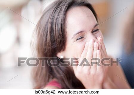 Young woman covering mouth in delight View Large Photo Image Stock Image - Young woman covering mouth in delight. Fotosearch