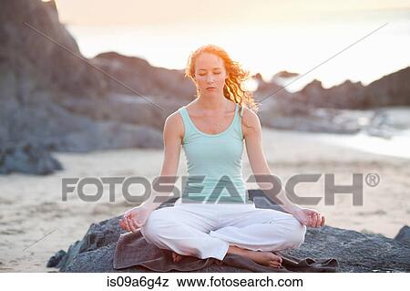 Stock Photo - Young woman doing yoga on beach. Fotosearch