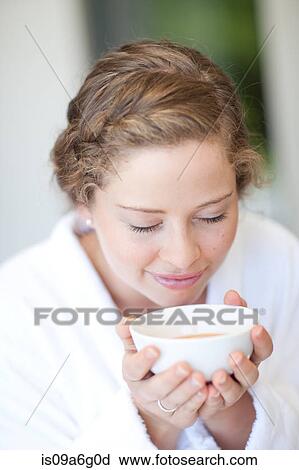 Stock Image - Young woman drinking tea with eyes closed. Fotosearch