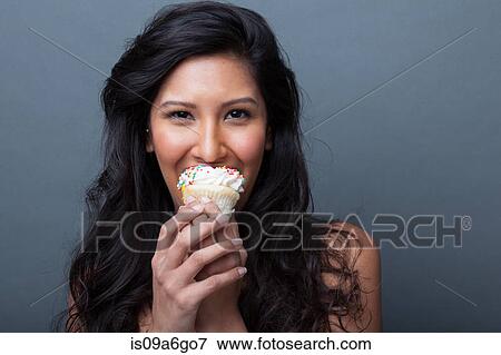 Stock Photo - Young woman eating cupcake. Fotosearch