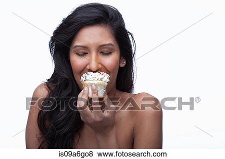Stock Photo - Young woman eating cupcake. Fotosearch