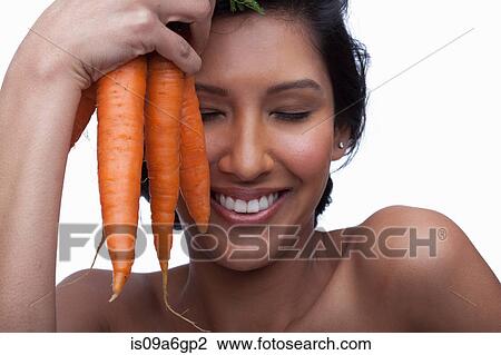Young woman holding bunch of carrots View Large Photo Image Stock Image - Young woman holding bunch of carrots. Fotosearch
