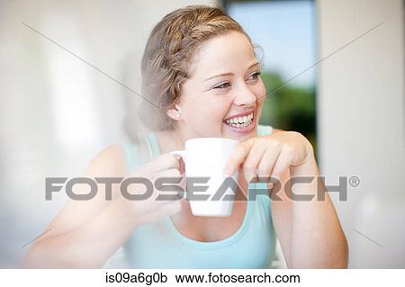 Stock Image - Young woman holding mug. Fotosearch