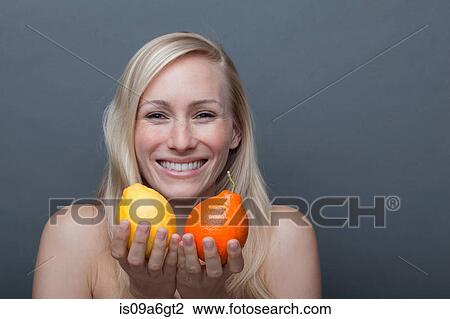 Stock Image - Young woman holding orange and lemon. Fotosearch