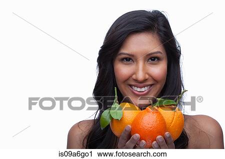 Stock Image - Young woman holding oranges. Fotosearch