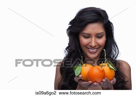 Stock Image - Young woman holding oranges. Fotosearch