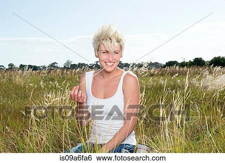Stock Photograph - Young woman in grassy field. Fotosearch