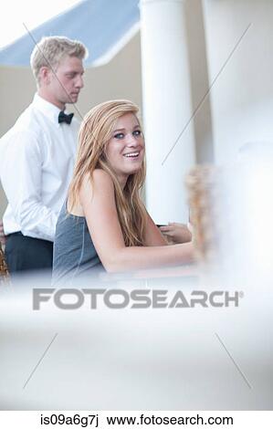 Stock Image - Young woman in restaurant with waiter. Fotosearch