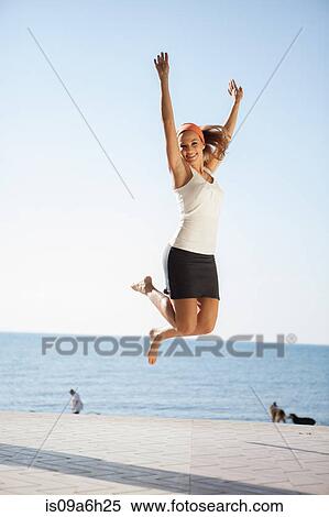 Stock Photography - Young woman jumping mid air. Fotosearch