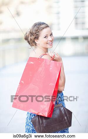 Stock Image - Young woman looking over shoulder at camera. Fotosearch