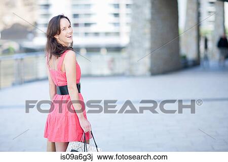 Young woman looking over shoulder at camera View Large Photo Image Stock Image - Young woman looking over shoulder at camera. Fotosearch