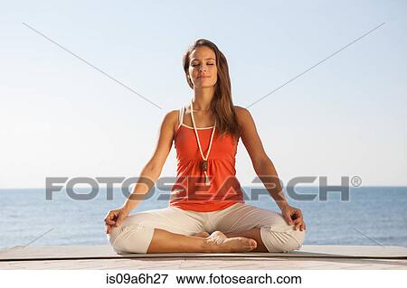Stock Photo - Young woman meditating by sea. Fotosearch