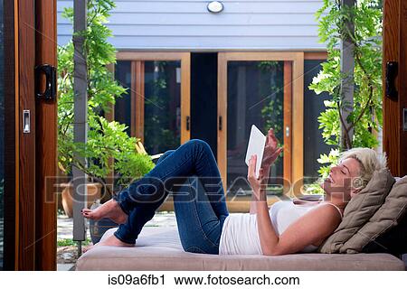 Young woman on sofa using digital tablet View Large Photo Image Stock Image - Young woman on sofa using digital tablet. Fotosearch
