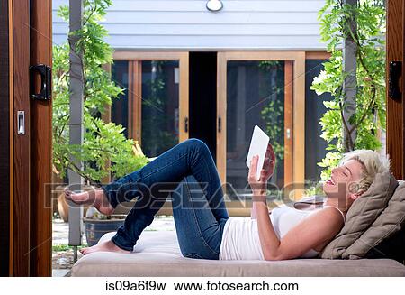 Stock Photo - Young woman on sofa using digital tablet. Fotosearch