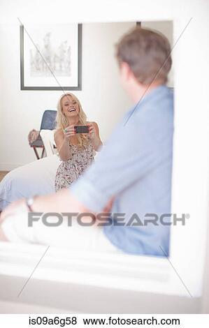 Young woman photographing man with smartphone View Large Photo Image Stock Photo - Young woman photographing man with smartphone. Fotosearch