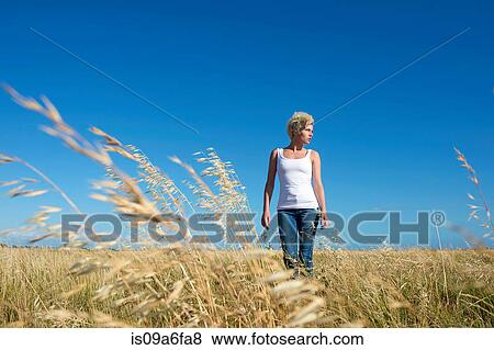 Young woman standing in grassy field View Large Photo Image Stock Photo - Young woman standing in grassy field. Fotosearch