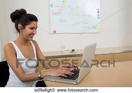 Stock Image - Young woman using laptop. Fotosearch
