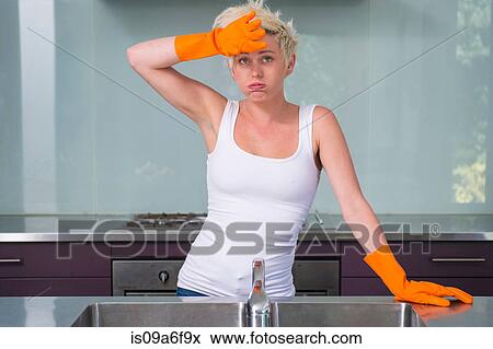 Stock Photo - Young woman wearing orange washing up gloves. Fotosearch