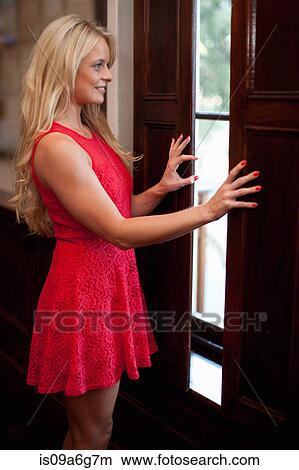 Young woman wearing red dress by door View Large Photo Image Picture - Young woman wearing red dress by door. Fotosearch