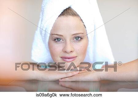 Stock Image - Young woman wearing towel on head with chin on hands. Fotosearch
