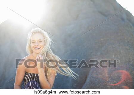 Picture - Young woman with long blonde hair on rocks. Fotosearch