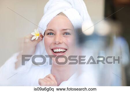 Stock Photography - Young woman with towel on head and flower behind ear. Fotosearch