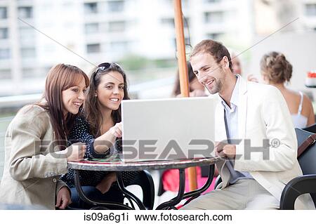 Young women and young man using laptop in cafe View Large Photo Image Stock Image - Young women and young man using laptop in cafe. Fotosearch