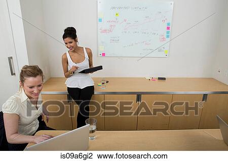 Young women at work, one woman using laptop View Large Photo Image Stock Image - Young women at work, one woman using laptop. Fotosearch