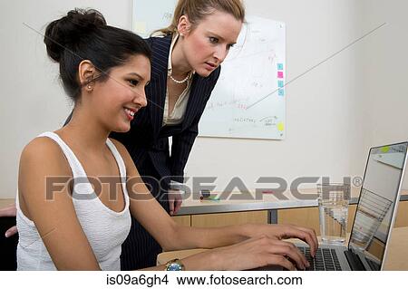 Picture - Young women at work using laptop. Fotosearch