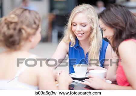 Young women chatting with friends at cafe View Large Photo Image Stock Photo - Young women chatting with friends at cafe. Fotosearch
