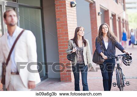 Young women on sidewalk with bicycle View Large Photo Image Stock Image - Young women on sidewalk with bicycle. Fotosearch