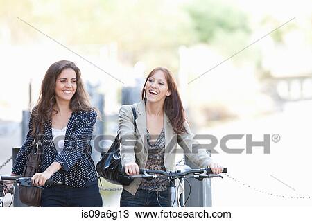Young women pushing bicycles View Large Photo Image Stock Image - Young women pushing bicycles. Fotosearch