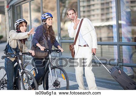 Young women with bicycles asking young man for directions View Large Photo Image Stock Image - Young women with bicycles asking young man for directions. Fotosearch