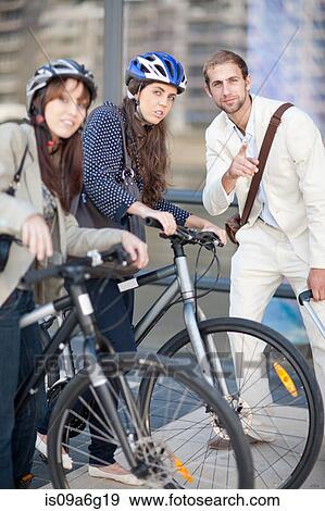 Young women with bicycles asking young man for directions View Large Photo Image Stock Photo - Young women with bicycles asking young man for directions. Fotosearch