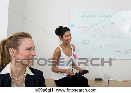 Young women with whiteboard in background View Large Photo Image Stock Image - Young women with whiteboard in background. Fotosearch