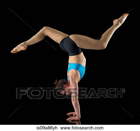 Stock Image - Acrobat performing handstand in front of black background. Fotosearch
