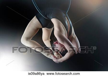 Aerialist performing on hoop in front of black background View Large Photo Image Stock Image - Aerialist performing on hoop in front of black background. Fotosearch