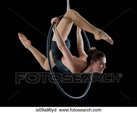 Aerialist performing on hoop in front of black background View Large Photo Image Stock Image - Aerialist performing on hoop in front of black background. Fotosearch