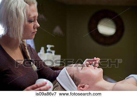 Beautician performing facial on woman, lying with eyes closed View Large Photo Image Stock Photo - Beautician performing facial on woman, lying with eyes closed. Fotosearch
