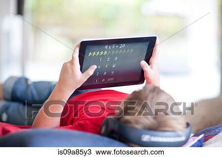 Boy on bed listening to music and using digital tablet View Large Photo Image Stock Image - Boy on bed listening to music and using digital tablet. Fotosearch