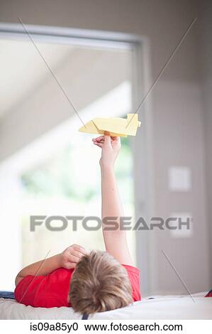 Boy on bed playing with paper aeroplane View Large Photo Image Stock Image - Boy on bed playing with paper aeroplane. Fotosearch