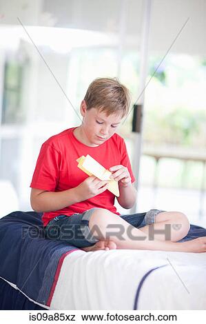 Boy on bed playing with paper aeroplane View Large Photo Image Stock Photo - Boy on bed playing with paper aeroplane. Fotosearch