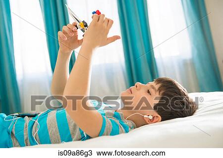 Boy wearing earphones and playing with toy View Large Photo Image Stock Image - Boy wearing earphones and playing with toy. Fotosearch