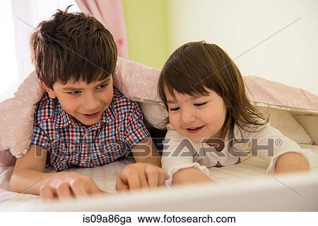 Brother and sister lying on bed View Large Photo Image Stock Image - Brother and sister lying on bed. Fotosearch