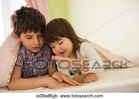 Brother and sister playing game in bed View Large Photo Image Stock Image - Brother and sister playing game in bed. Fotosearch