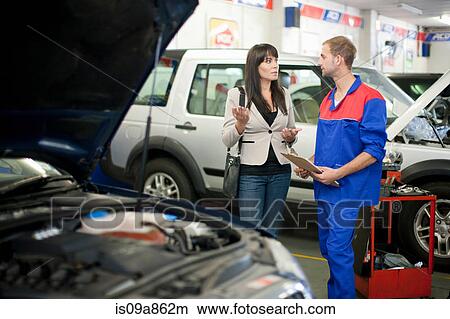 Picture - Car mechanic and customer discussing car repair. Fotosearch
