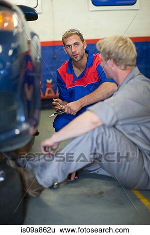 Car mechanics discussing and analyzing car repair View Large Photo Image Stock Photograph - Car mechanics discussing and analyzing car repair. Fotosearch